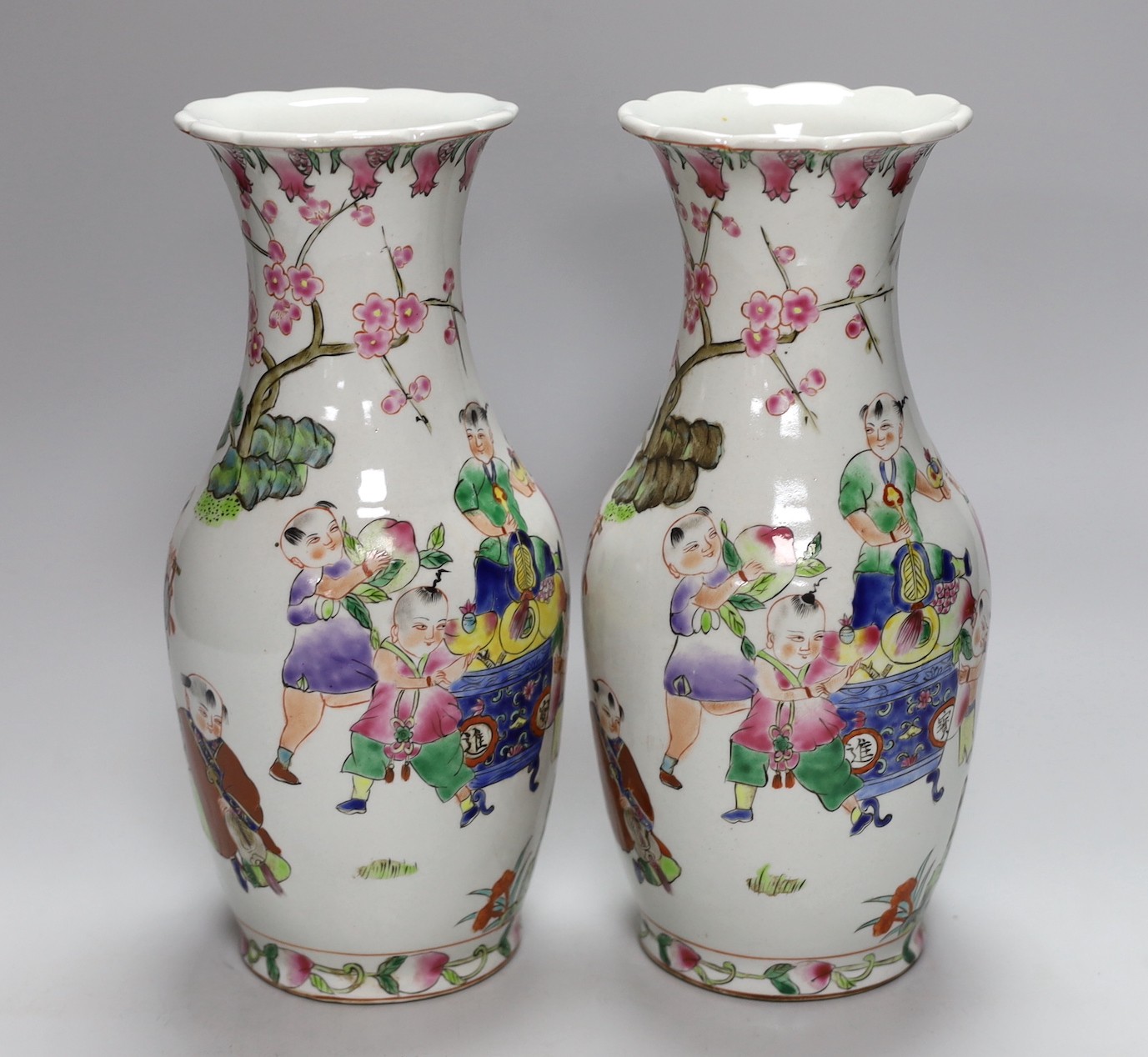 A pair of Chinese Famille Rose ‘boys’ vases, 25cms high